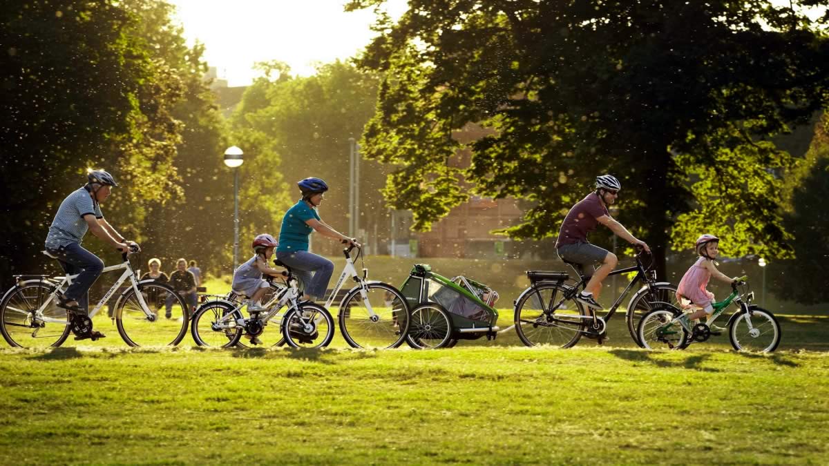 Adults and children cycling through a park
